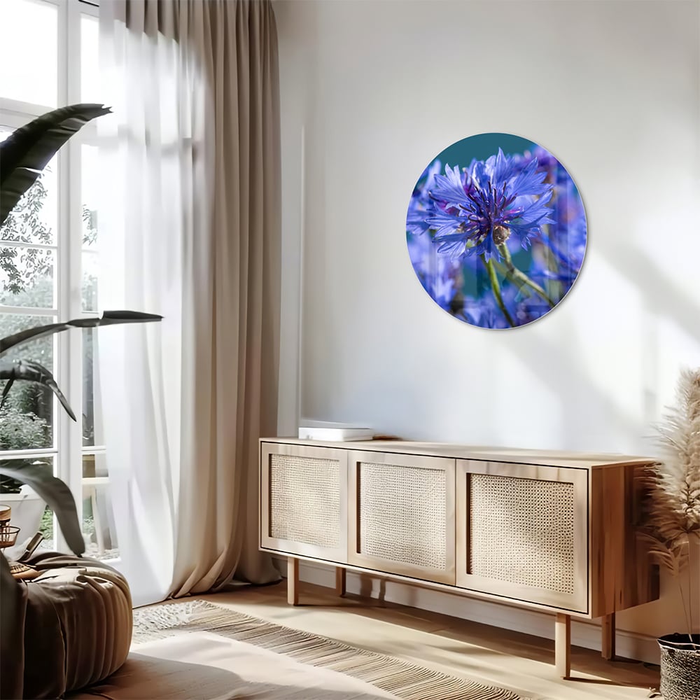 Een glazen schilderij met paarse bloemen op een witte muur, in een sfeervolle woonkamer.