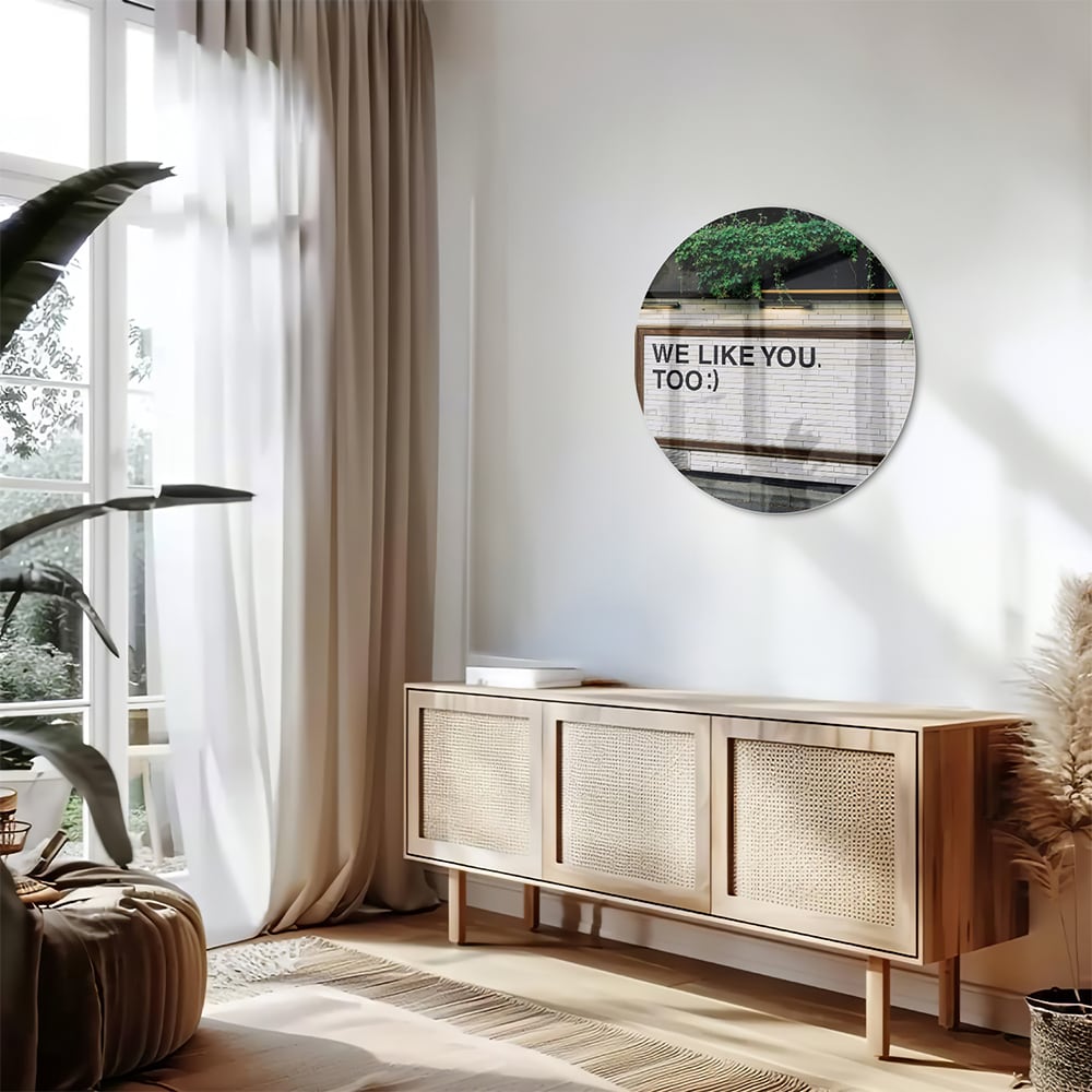 Glas schilderij met de tekst 'We Like You Too' en groene planten achtergronden.