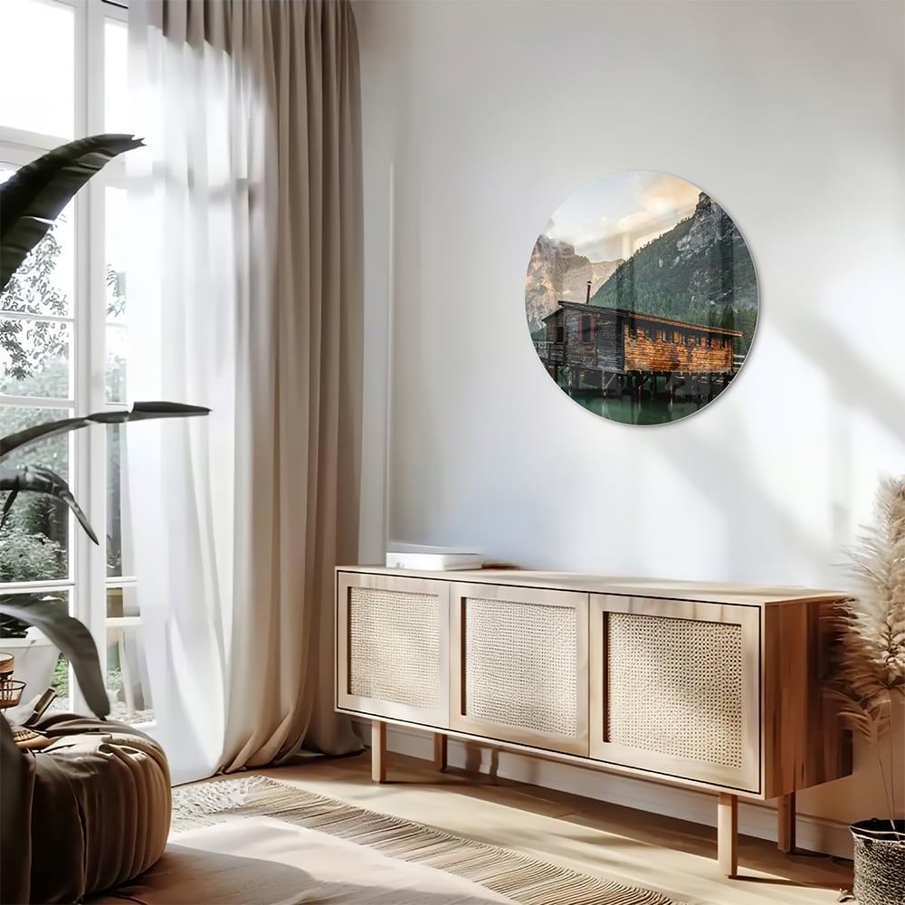 Glazen schilderij van een berghut aan een kalm meer met bergen op de achtergrond.