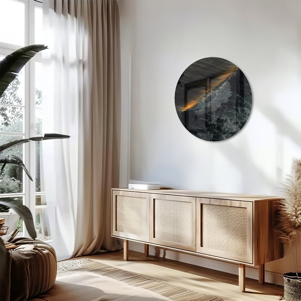 Zwart glazen schilderij van een zeegezicht met gouden accenten, hangt aan een lichtgekleurde muur.