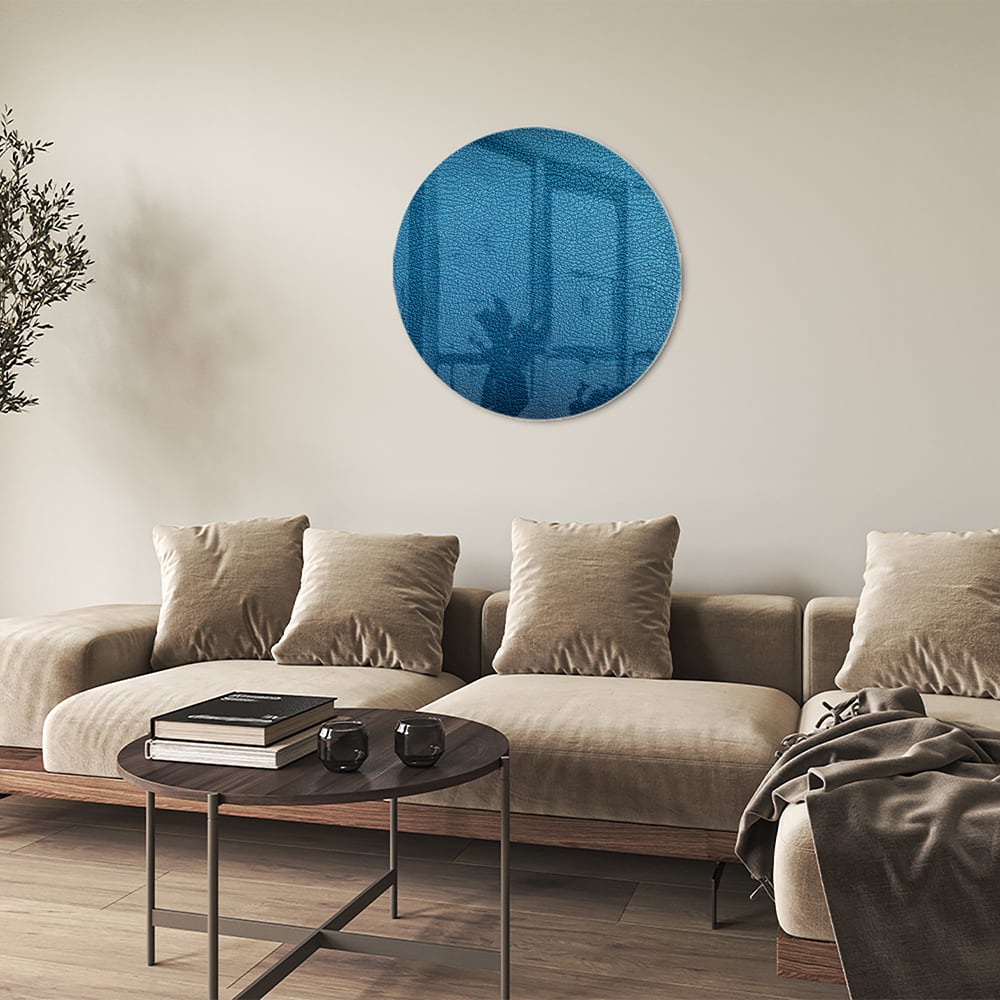 Blauw glazen schilderij met reflecties aan de muur in een moderne woonkamer.