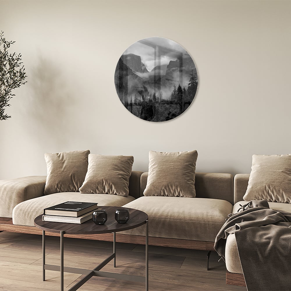 Zwart-wit glazen schilderij van een sereen berglandschap aan de muur.