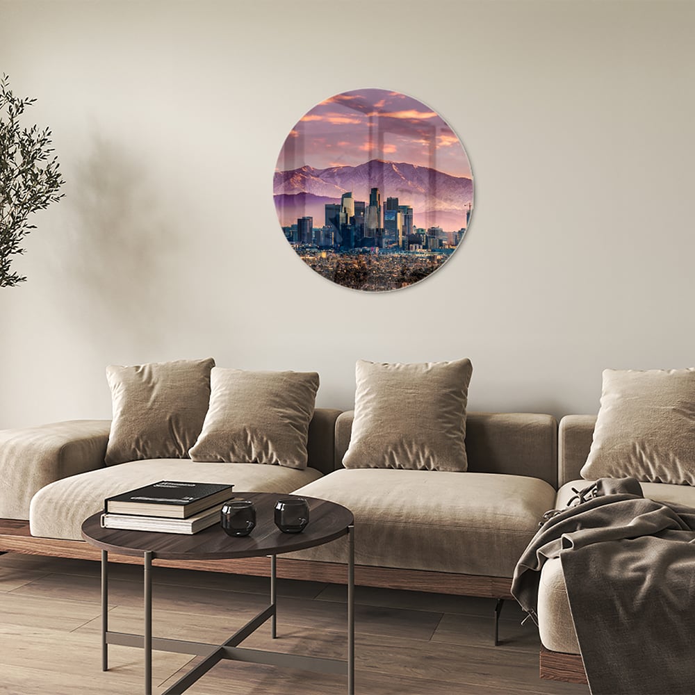Glazen schilderij van een stadspanorama bij zonsondergang met bergen op de achtergrond.