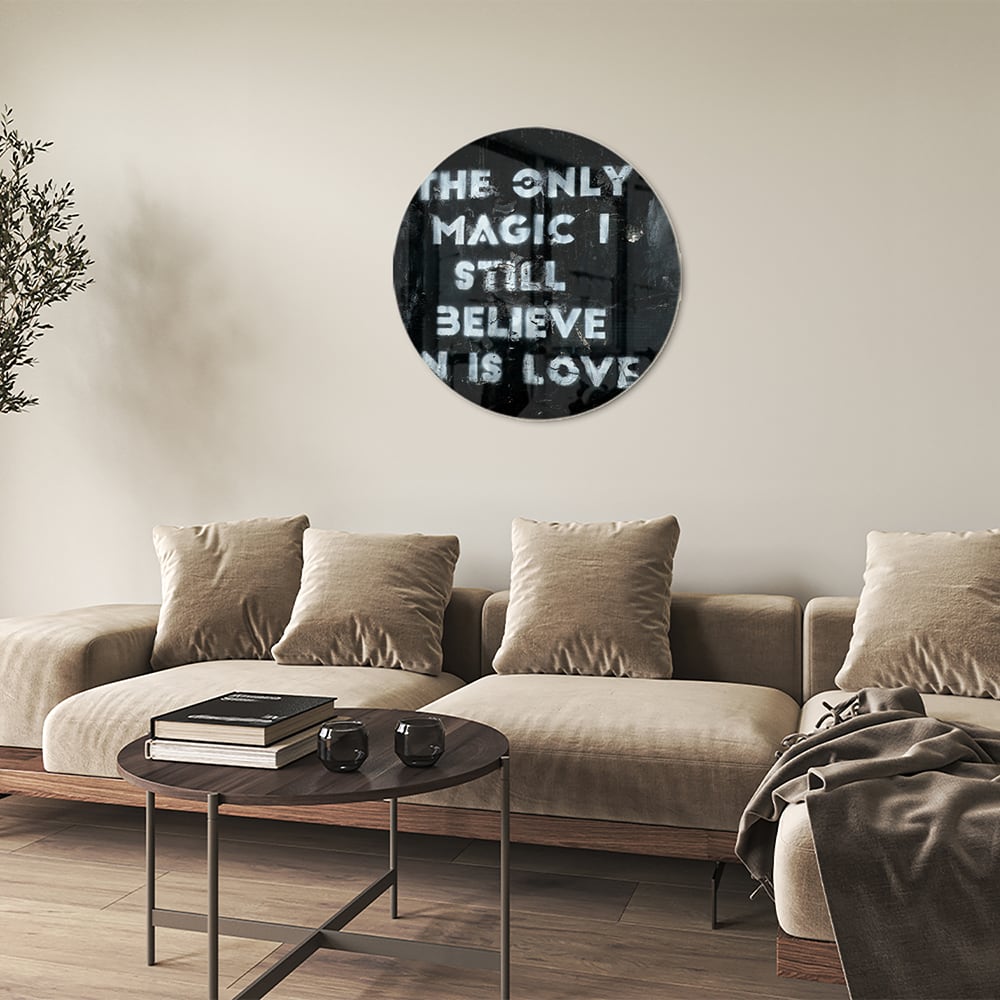 Glazen schilderij met de tekst 'The only magic I still believe in is love', hangt aan de muur in een lichte woonkamer.