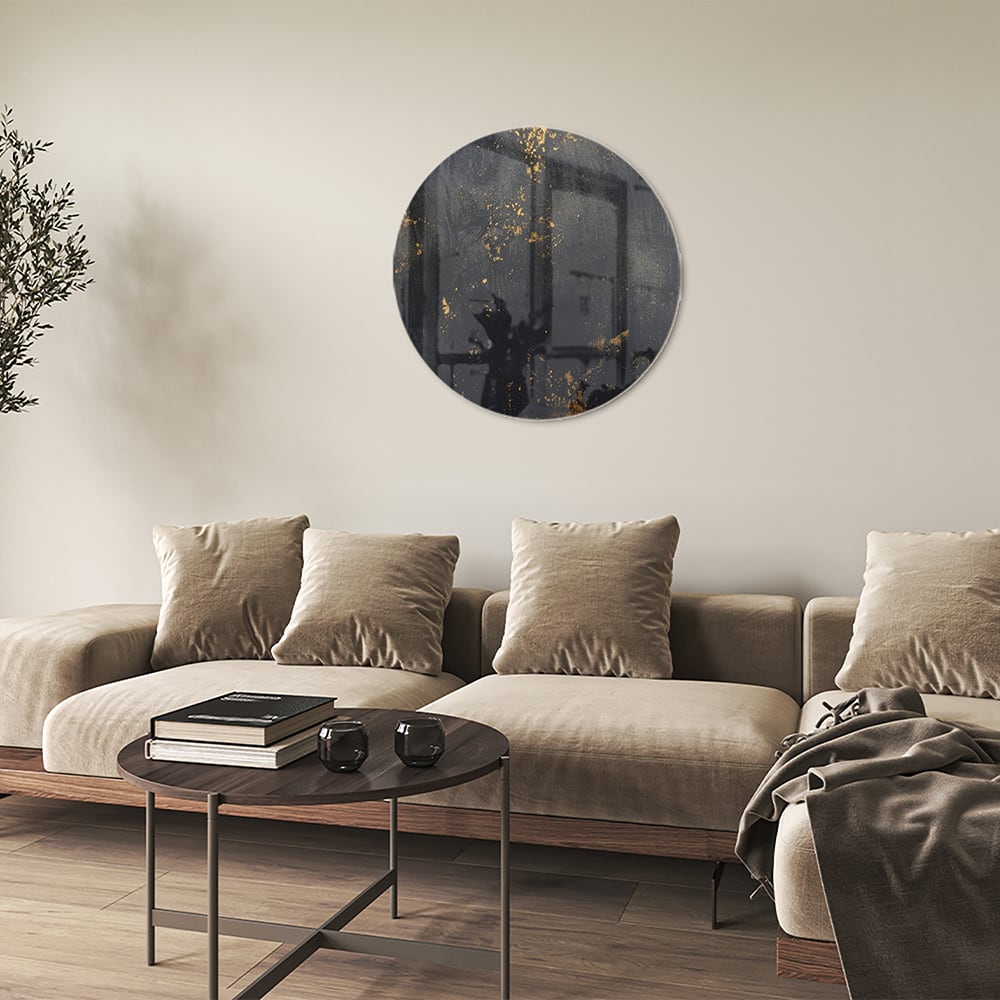 Glazen schilderij met een zwart oppervlak en gouden accenten hangt aan de muur in een moderne woonkamer.