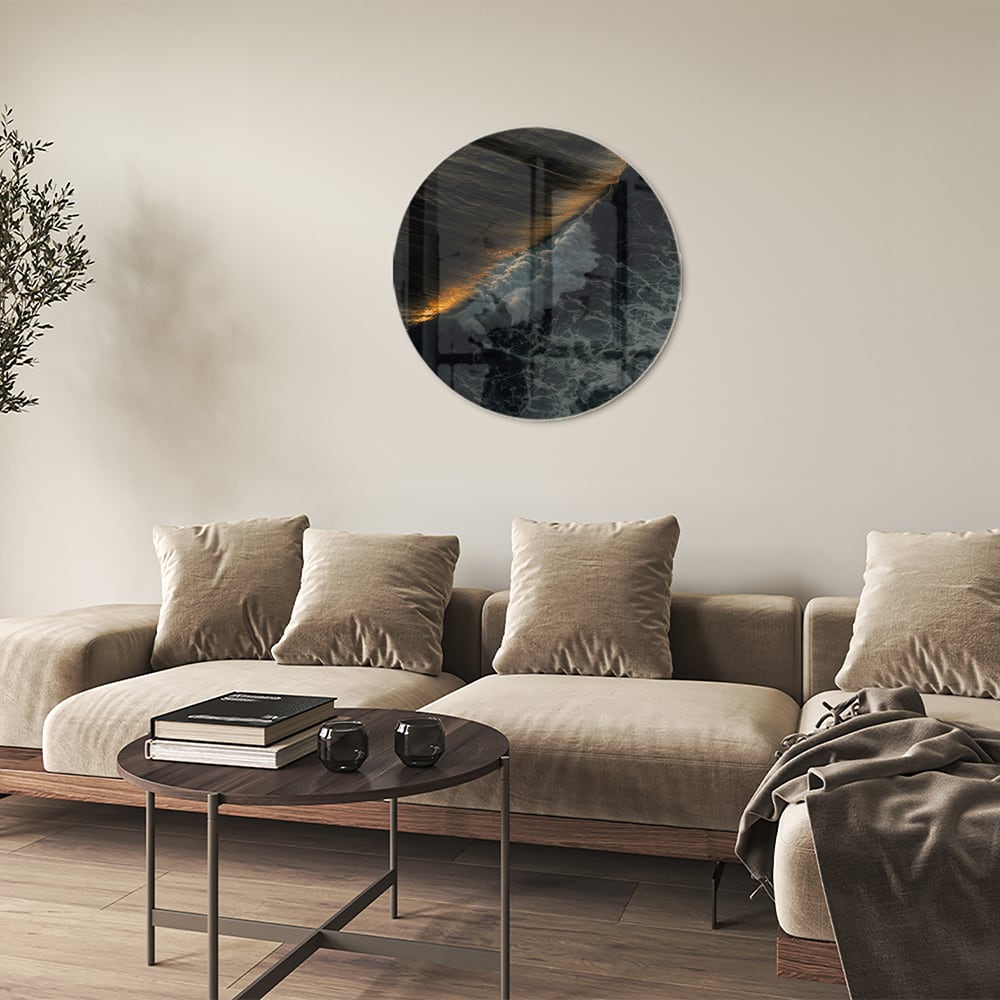 Zwart glazen schilderij van een zeegezicht met gouden accenten, hangt aan een lichtgekleurde muur.