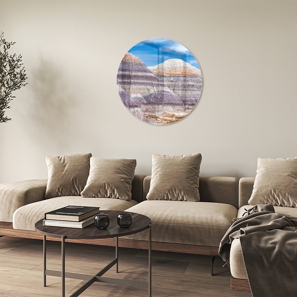 Glazen schilderij van bergen met een blauwe lucht in een moderne woonkamer.