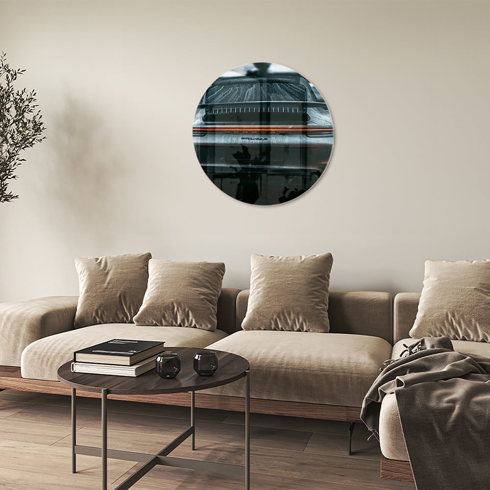 Glazen schilderij van een sportwagen aan de muur in een lichte woonkamer.