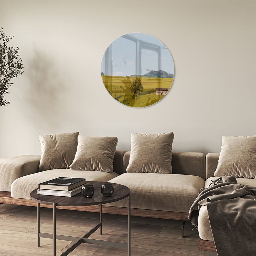 Glazen schilderij met groene heuvels en boerderijen op een witte muur.