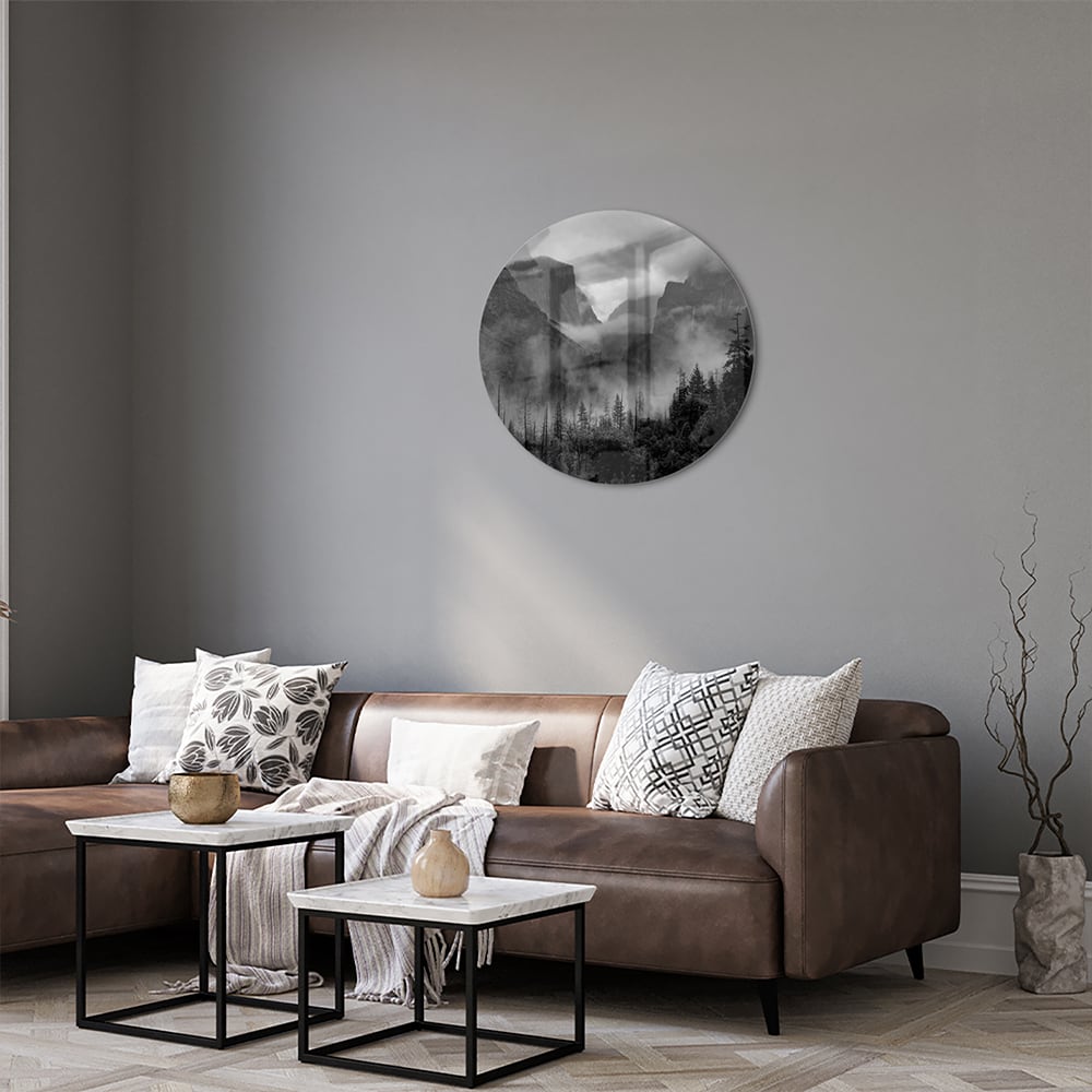 Zwart-wit glazen schilderij van een sereen berglandschap aan de muur.