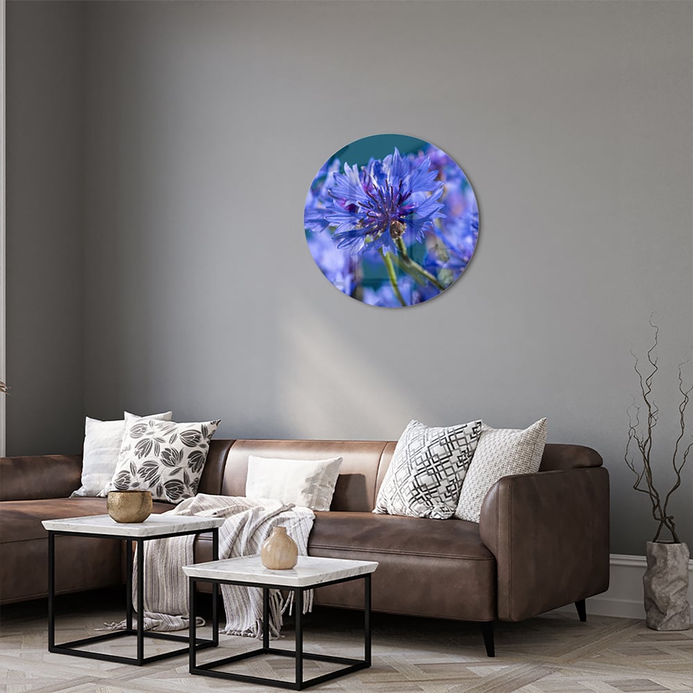 Een glazen schilderij met paarse bloemen op een witte muur, in een sfeervolle woonkamer.