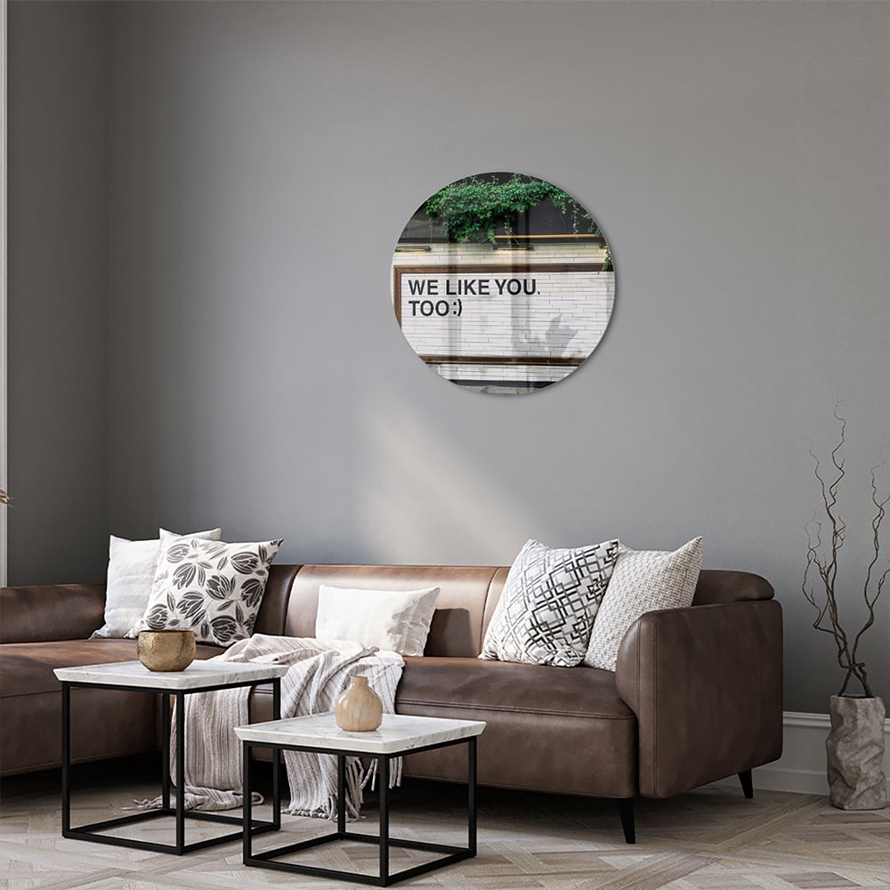 Glas schilderij met de tekst 'We Like You Too' en groene planten achtergronden.