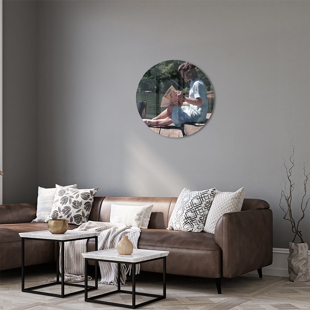 Glazen schilderij van een vrouw die aan het water leest in een serene omgeving.