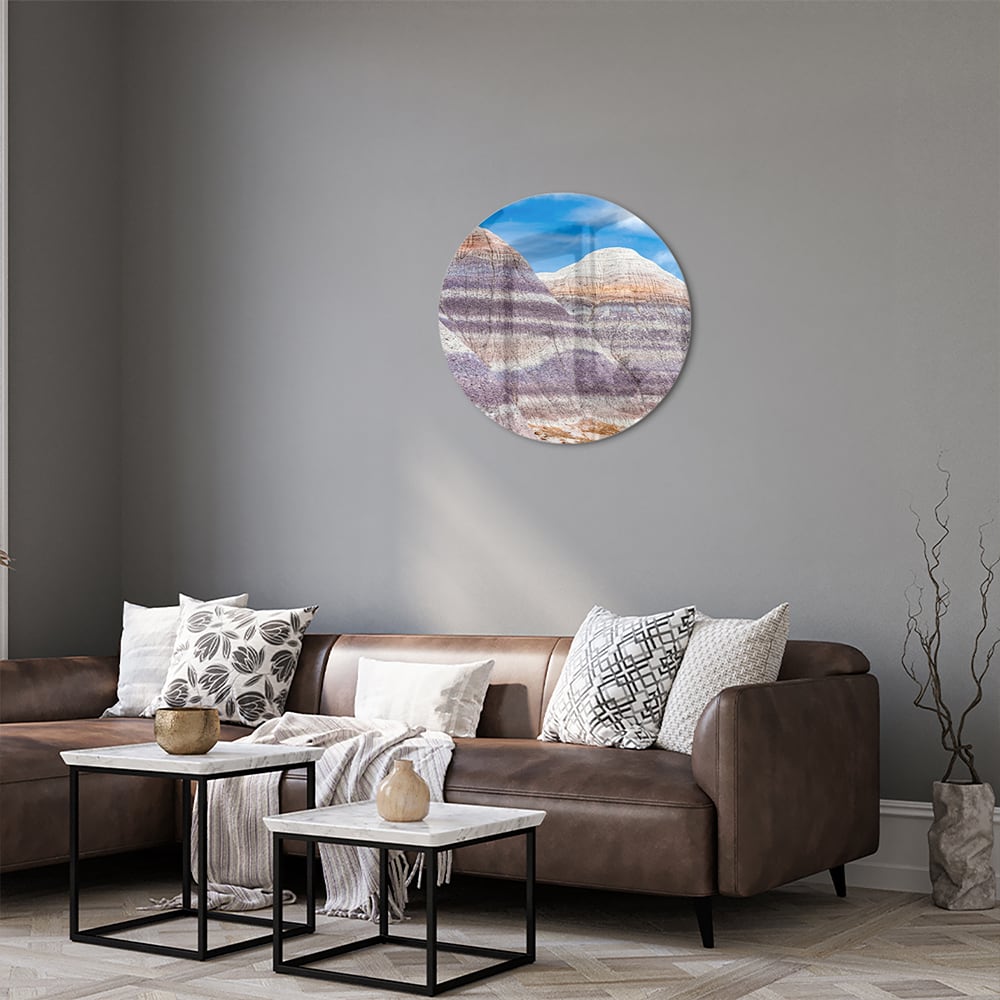 Glazen schilderij van bergen met een blauwe lucht in een moderne woonkamer.